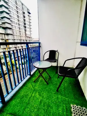 two chairs and a table on a balcony with green grass at Comfystay at Sea Residences in Manila