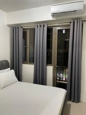 a bedroom with a bed and a window with curtains at Walking Distance to Mall of Asia - Spacious Condo with Hot Shower and Balcony in Manila