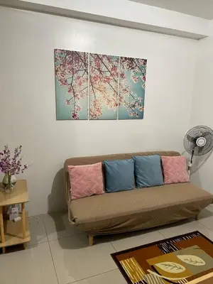 a living room with a couch and a painting on the wall at Walking Distance to Mall of Asia - Spacious Condo with Hot Shower and Balcony in Manila