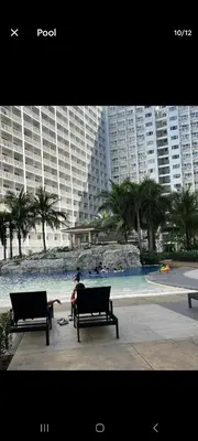 a person sitting on two benches in front of a fountain at Walking Distance to Mall of Asia - Spacious Condo with Hot Shower and Balcony in Manila