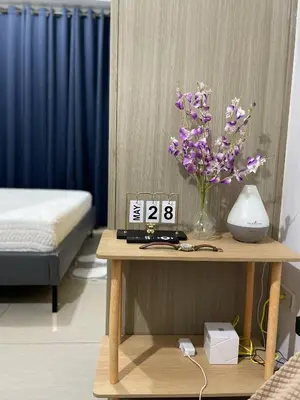 a table with a clock and a vase of purple flowers at Walking Distance to Mall of Asia - Spacious Condo with Hot Shower and Balcony in Manila