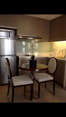 a kitchen with a table and two chairs and a table with flowers on it at Makati 1BR High Floor in Manila