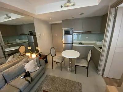 a living room with a couch and a table and a kitchen at Makati 1BR High Floor in Manila