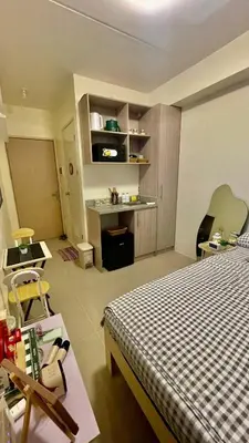 a bedroom with a bed and a table and a desk at The Cozy Fabb in Manila