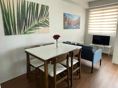 a living room with a table with a vase of flowers on it at Warm Modern Condo Apartment with Pool & Balcony - East Residences Ortigas Pasig City in Manila