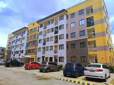 a large apartment building with cars parked in a parking lot at Warm Modern Condo Apartment with Pool & Balcony - East Residences Ortigas Pasig City in Manila