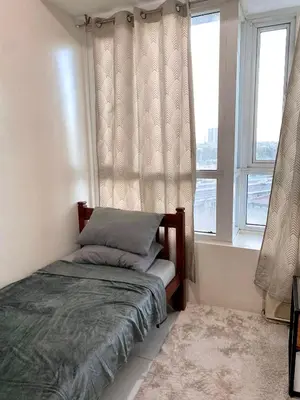 a bed in a room with two windows at Spacious 2br condo at Quezon City Mezza Residences 1 in Manila