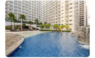 a person holding an umbrella in a swimming pool with buildings at Porongs Oasis in Manila