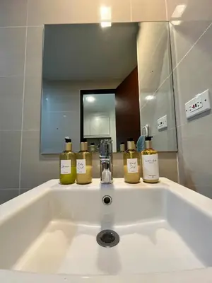 a bathroom sink with four bottles of oils on it at Cozy 1br unit in Uptown BGC in Manila