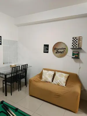 a couch in a room with a table and a sign at Staycation Zone in Manila