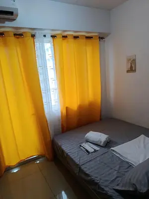 a small bedroom with yellow curtains and a bed at Staycation Zone in Manila