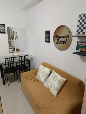 a couch sitting in a living room with two pillows at Staycation Zone in Manila