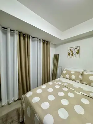 a bedroom with a large bed and curtains at SM Bicutan Escape Staycation in Manila