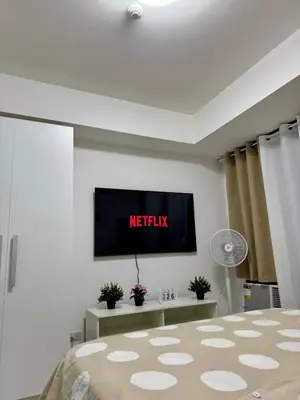 a bedroom with a tv on the wall and a bed at SM Bicutan Escape Staycation in Manila