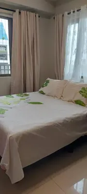 a bed with white sheets and green flowers on it at Jovy Place At Shore Residences&Sea Residences near Moa in Manila
