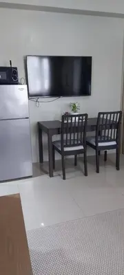 a kitchen with a table and two chairs and a television at Jovy Place At Shore Residences&Sea Residences near Moa in Manila
