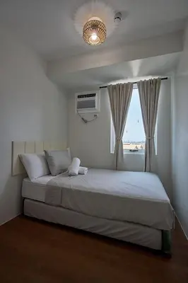 a bedroom with a large bed with a window at I-LAND Residences Sucat near NAIA w Wifi free parking in Manila