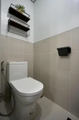 a bathroom with a toilet and a shelf with books at I-LAND Residences Sucat near NAIA w Wifi free parking in Manila