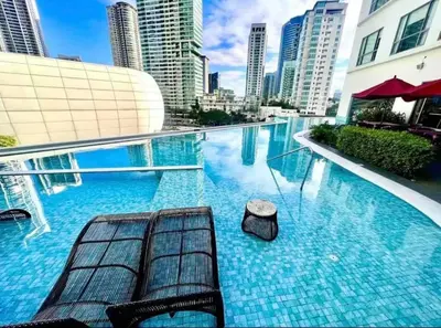 a swimming pool with two benches in a city at The Hotel Residences at Acqua Tower in Manila