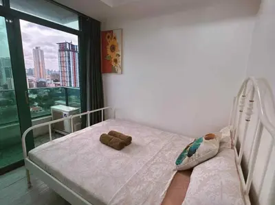 a teddy bear sitting on a bed in a room with a window at Ocean view malate manila in Manila