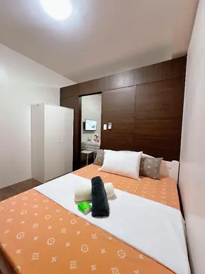 a bedroom with a large bed with an orange and white bedspread at air residences in Manila