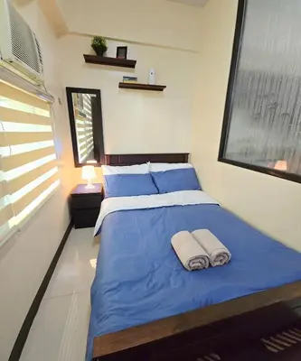 a bedroom with a blue bed with towels on it at Studio unit near BGC and Makati in Manila