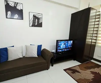 a living room with a couch and a flat screen tv at Studio unit near BGC and Makati in Manila