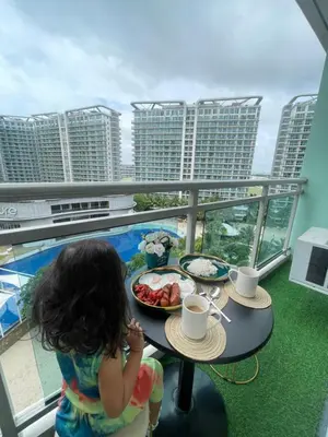 a little girl sitting at a table with a plate of food at Azure Urban Resorts by Rhome in Manila