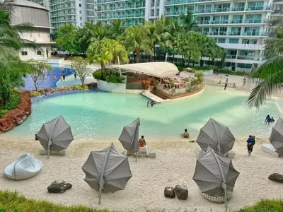 a large pool of water with umbrellas on a beach at Azure Urban Resorts by Rhome in Manila