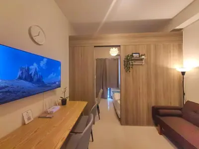 a living room with a couch and a television on a wall at 1BR Condotel with Balcony at FAME Residences #FM37-1 in Manila