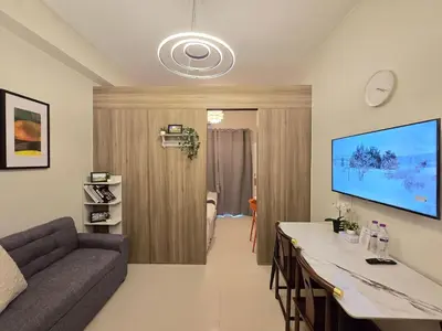 a living room with a couch and a television on the wall at 1BR Condotel with Balcony at FAME Residences #FM44-1 in Manila