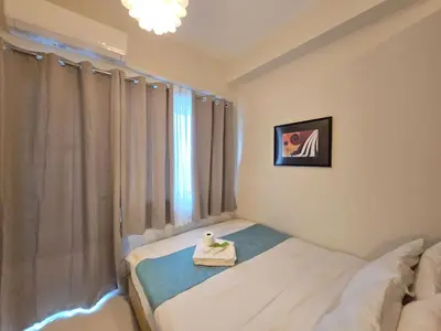 a white room with a bed and a window at 1BR Condotel with Balcony at FAME Residences #FM46-1 in Manila