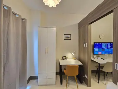 a room with a desk and a white cabinet and a table at 1BR Condotel with Balcony at FAME Residences #FM50-1 in Manila