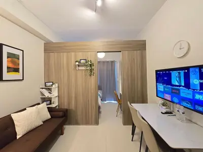 a living room with a desk and a large screen tv at 1BR Condotel with Balcony at FAME Residences #FM50-1 in Manila