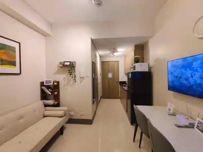a living room with a couch and a large screen tv at 1BR Condotel with Balcony at FAME Residences #FM51-1 in Manila