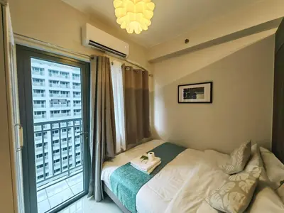 a bedroom with a bed and a large window at 1BR Condotel with Balcony at FAME Residences #FM51-1 in Manila