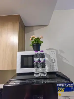 two bottles of water and a potted plant on top of a microwave at 1BR Condotel with Balcony at FAME Residences #FM47-1 in Manila
