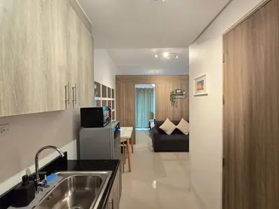 a kitchen with a sink and a living room at 1BR Condotel with Balcony at FAME Residences #FM49-1 in Manila