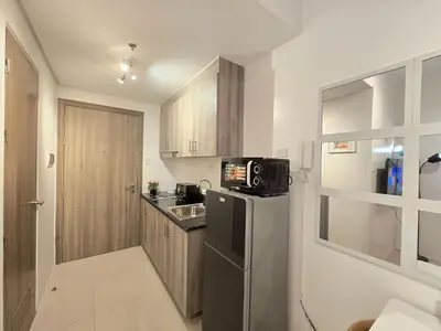 a small kitchen with a black refrigerator and a sink at 1BR Condotel with Balcony at FAME Residences #FM49-1 in Manila