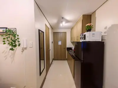 a small kitchen with a black refrigerator and a hallway at 1BR Condotel with Balcony at FAME Residences #FM52-1 in Manila