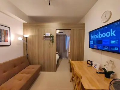 a living room with a couch and a large tv at 1BR Condotel with Balcony at FAME Residences #FM53-1 in Manila