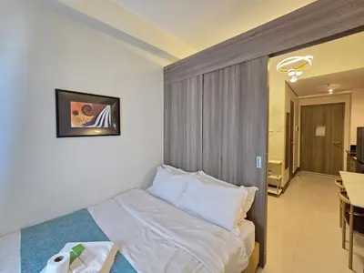 a bedroom with a bed with white sheets and pillows at 1BR Condotel with Balcony at FAME Residences #FM54-1 in Manila