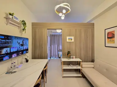 a living room with a long table and a television at 1BR Condotel with Balcony at FAME Residences #FM54-1 in Manila