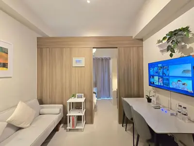 a living room with a white couch and a large tv at 1BR Condotel with Balcony at FAME Residences #FM57-1 in Manila