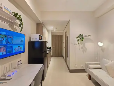a kitchen with a black refrigerator and a living room at 1BR Condotel with Balcony at FAME Residences #FM57-1 in Manila
