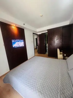 a bedroom with a bed with a tv on the wall at Poblacion Makati Condo in Manila