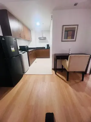 a kitchen with a refrigerator and a table and a chair at Poblacion Makati Condo in Manila