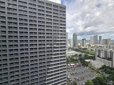 a tall white building with a city in the background at 1BR Condotel with Balcony at FAME Residences #FM60-1 in Manila