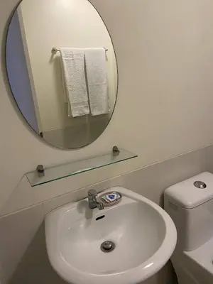 a bathroom with a sink and a mirror and a toilet at Lumiere Residences in Manila