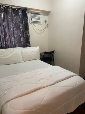 a bedroom with a bed and a window with a air conditioner at Lumiere Residences in Manila